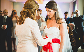 This is an image of a Bride with her mother who is wrapping the red scarf around her daughter at a Stolisma Ceremony